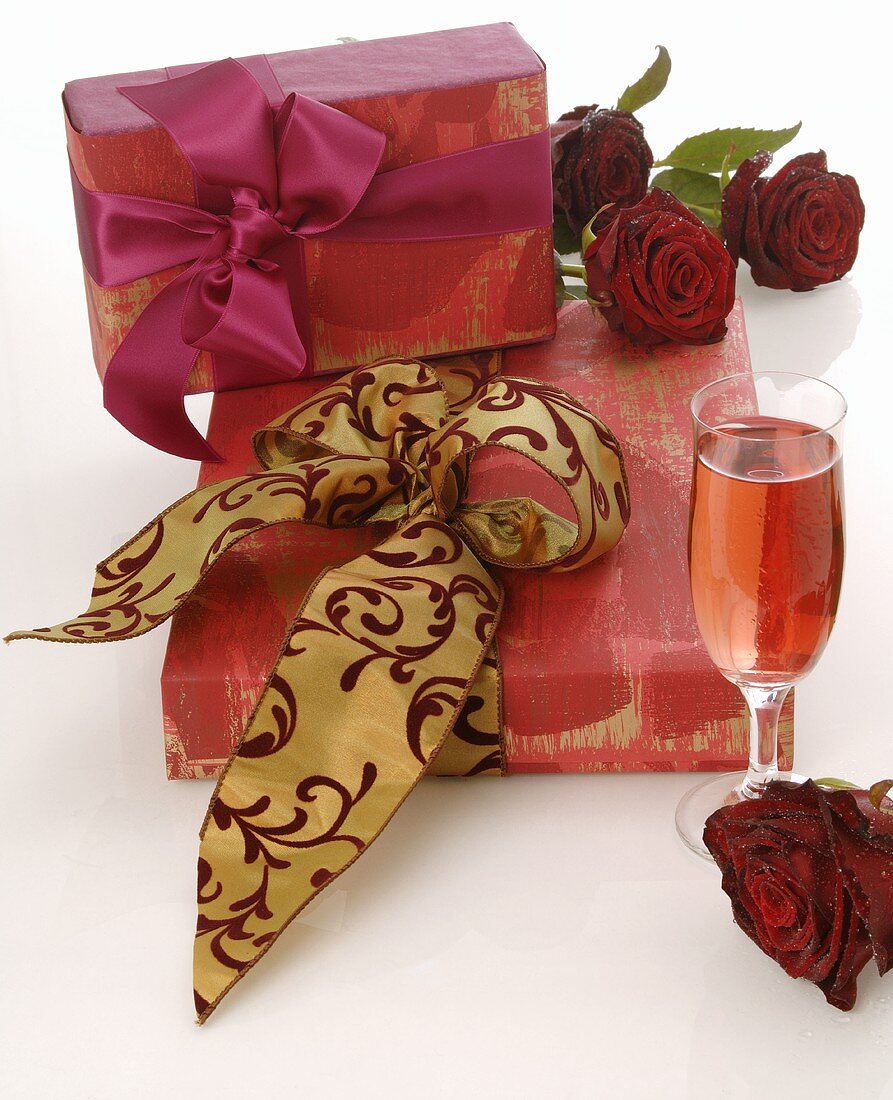 Gifts, red roses and glass of sparkling wine