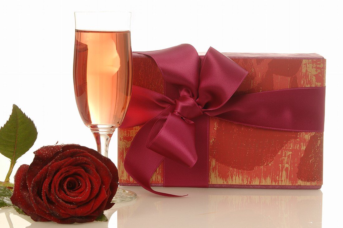 Geschenk, rote Rose und Sektglas