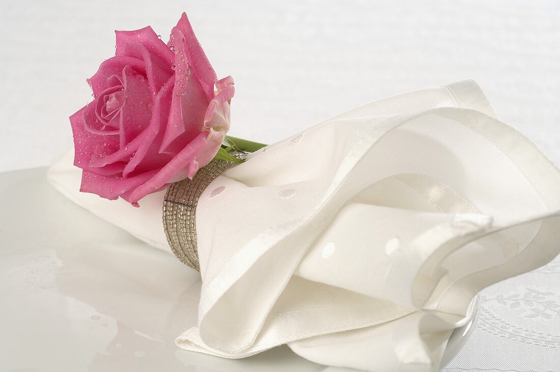Fabric napkin with pink rose on white plate