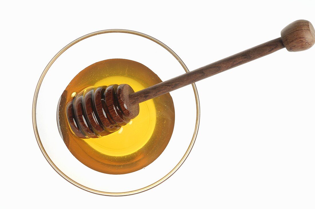 Honey and honey dipper in glass (overhead view)