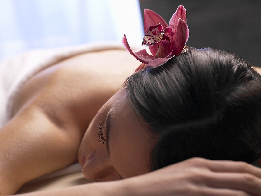 Frau mit Orchidee im Haar auf der Massagebank