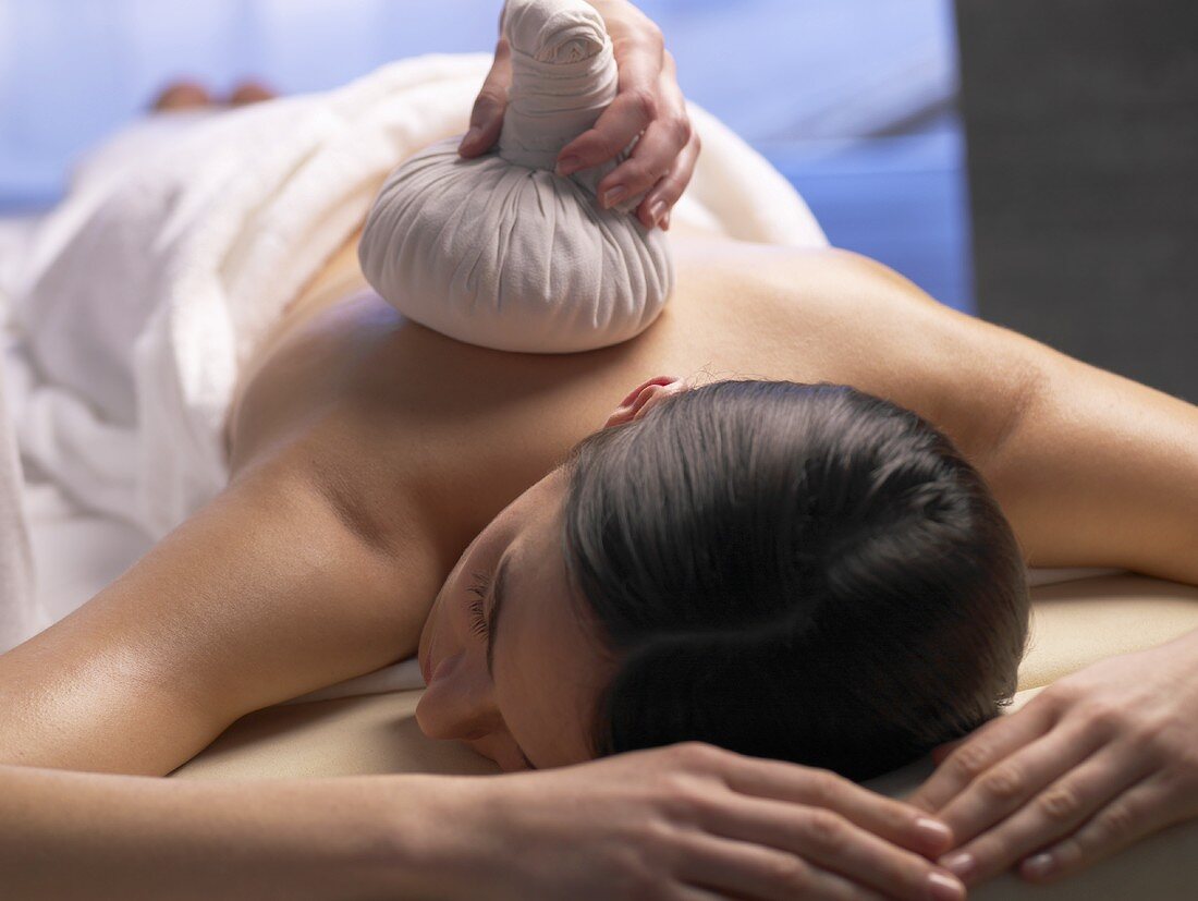 Woman on massage couch with compress