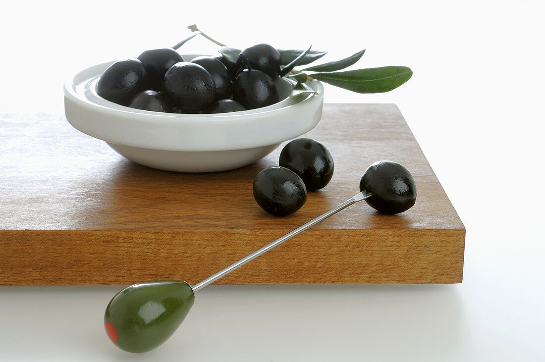 Black olives in small dish and on cocktail stick