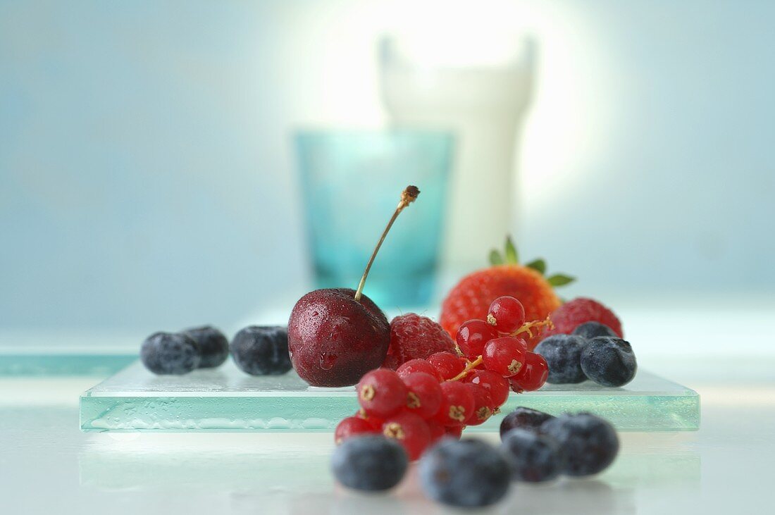 Beeren und Kirschen, Gläser im Hintergrund