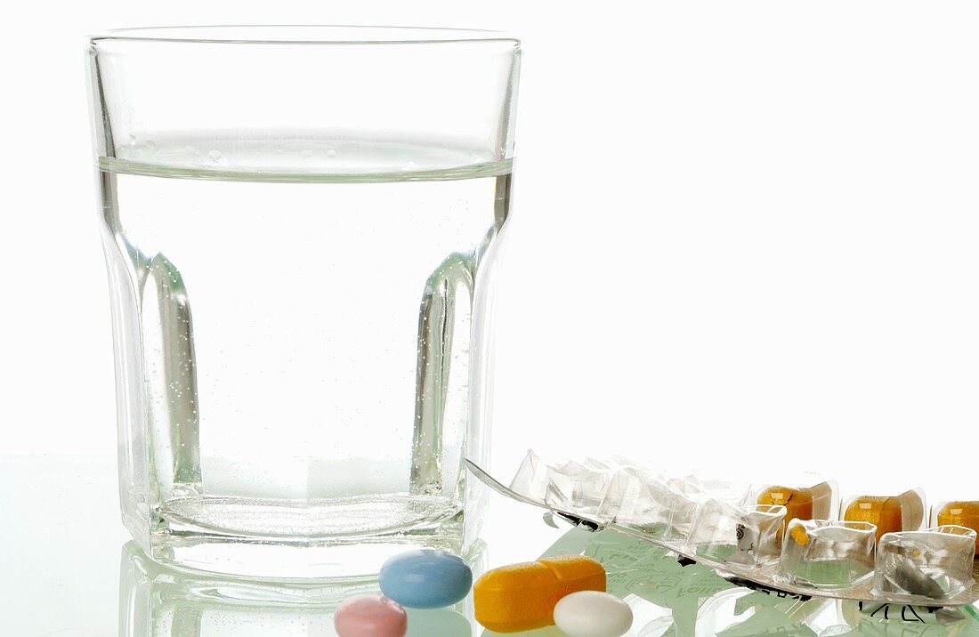 Wasserglas und verschiedene Tabletten