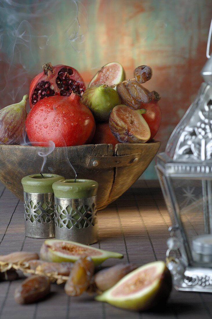 Pomegranates, figs and dates in wooden bowl, lantern