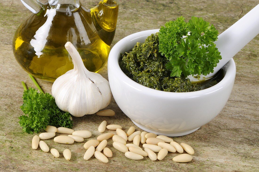 Parsley pesto in mortar surrounded by ingredients