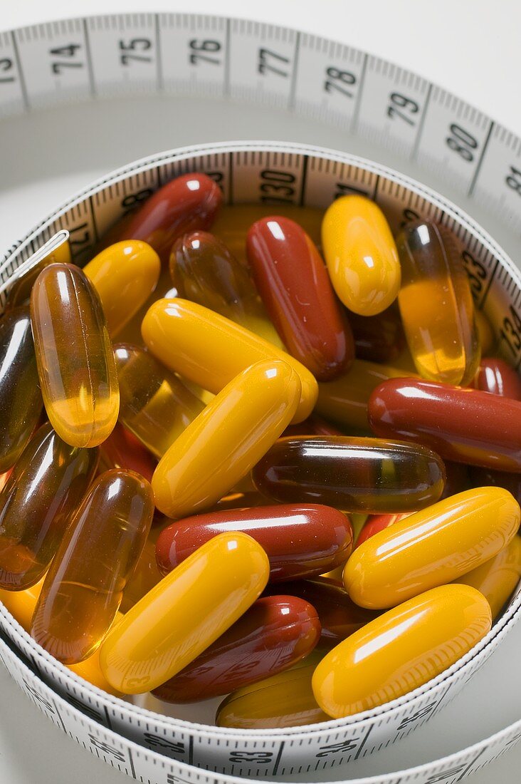 Assorted vitamin capsules and tape measure (close-up)
