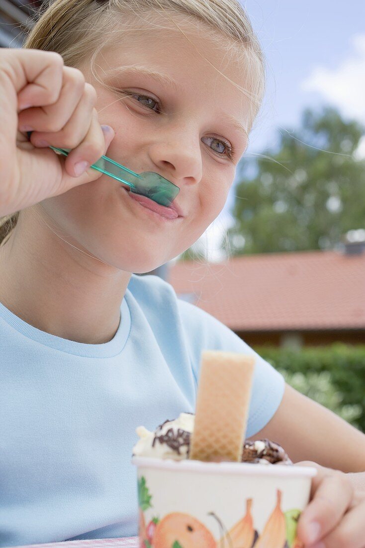 Mädchen isst Eisbecher im Freien