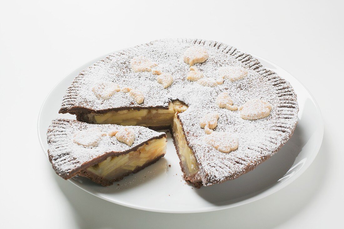 Apple pie dusted with icing sugar, a piece cut