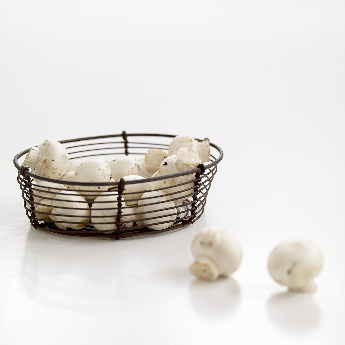 Fresh button mushrooms in wire basket