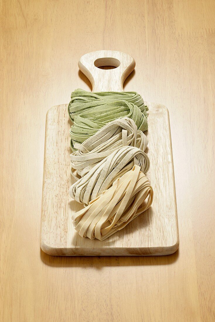 Chilli-, sage- and spinach fettuccine on wooden board