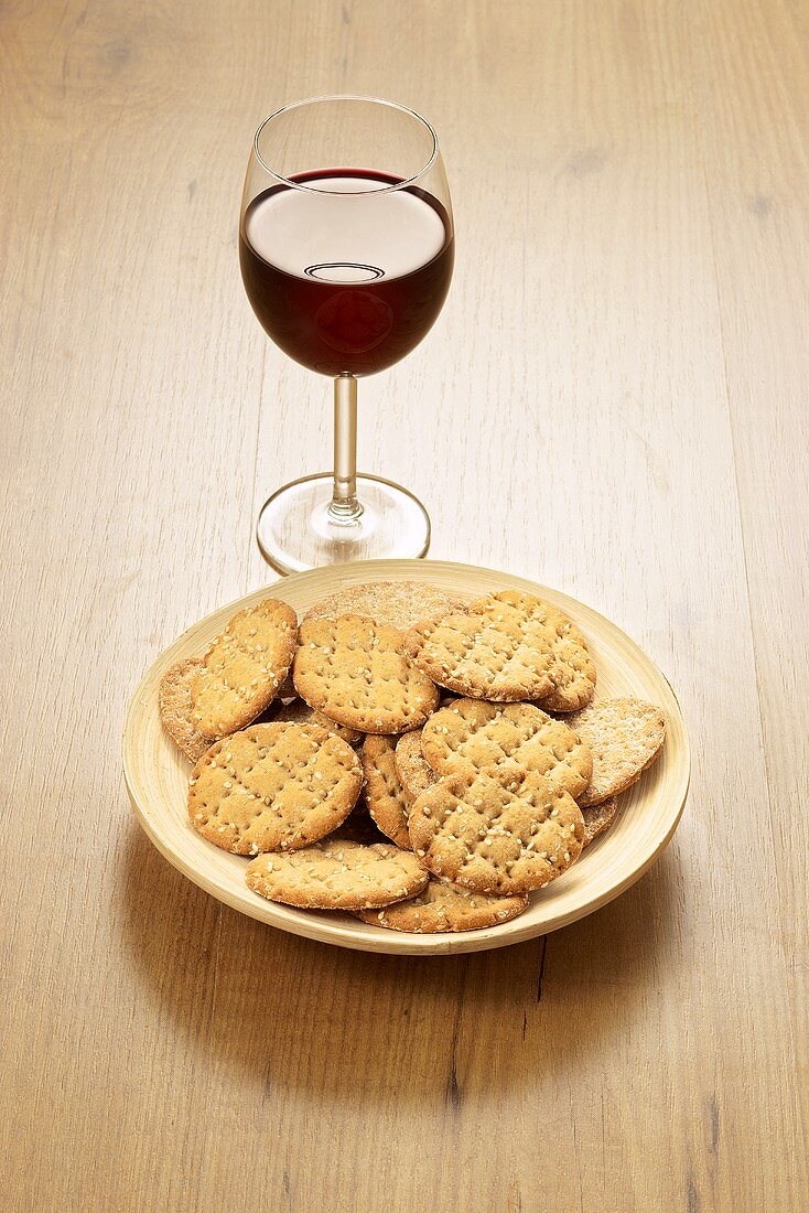 Schälchen mit Kräckers und ein Glas Rotwein