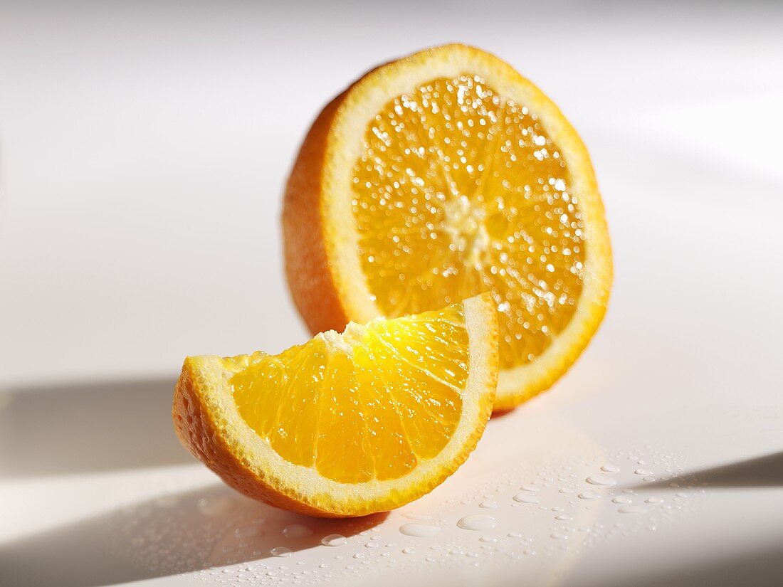 Orange wedge in front of half an orange