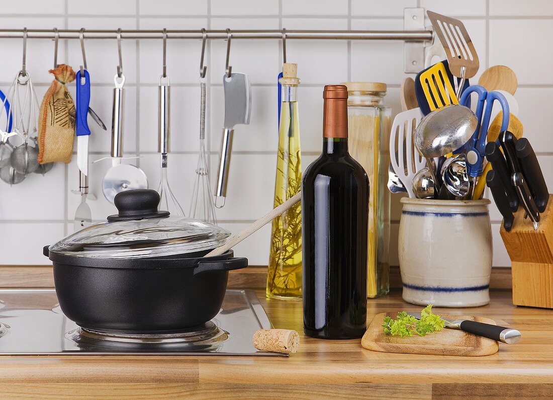 Cast-iron pan, bottle of red wine and various kitchen utensils