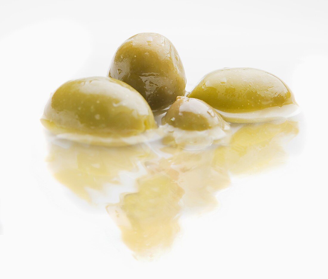 Four green olives in water