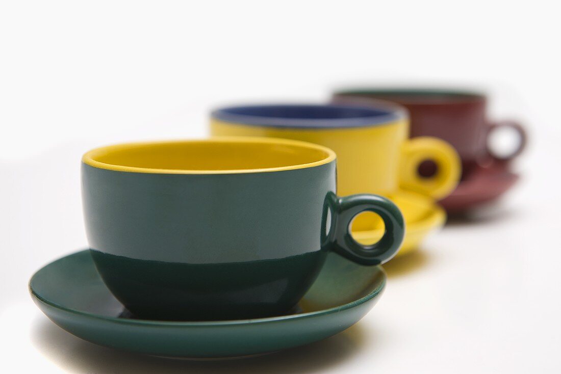 Three coloured cups and saucers in a row