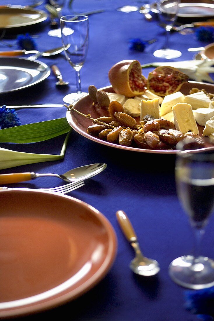 Käseteller mit Datteln und Granatäpfeln auf gedecktem Tisch