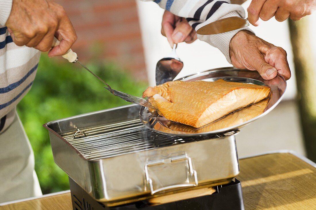 Salmon fillet being lifted from grill on to serving plate