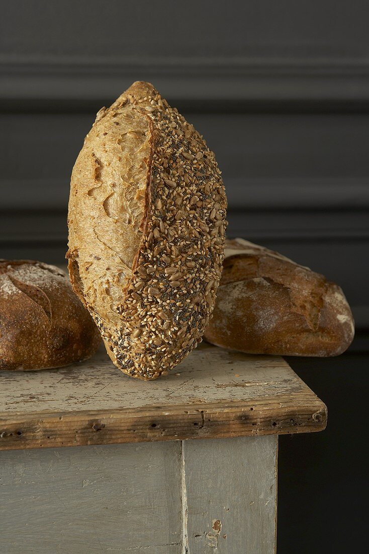 Three different rustic loaves of bread on a wooden table