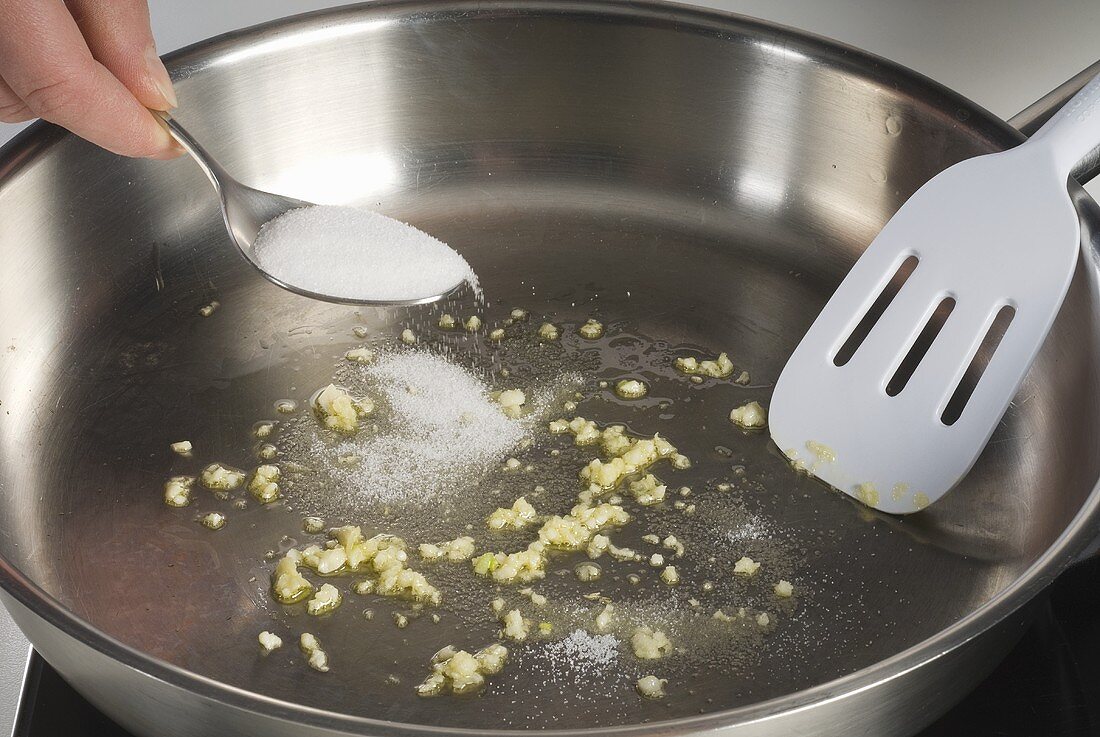 Knoblauch in der Pfanne; Zucker zugeben