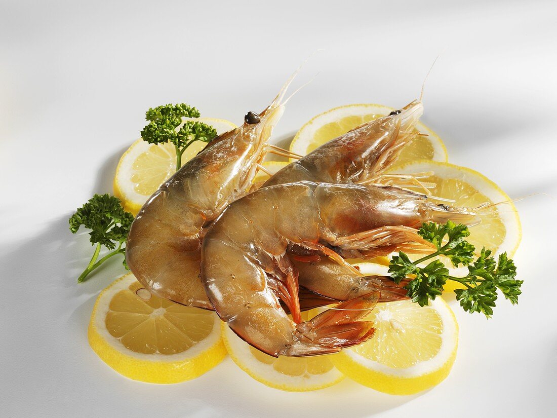 Three raw prawns on lemon slices with parsley