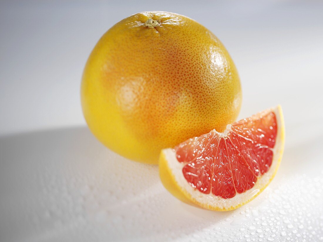 A whole grapefruit and a wedge of grapefruit