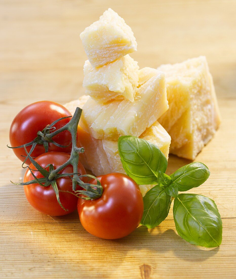 Tomatoes, basil and Parmesan on a wooden surface