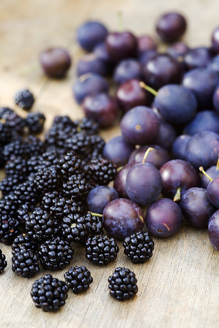 Zwetschgen und Brombeeren auf Holzuntergrund