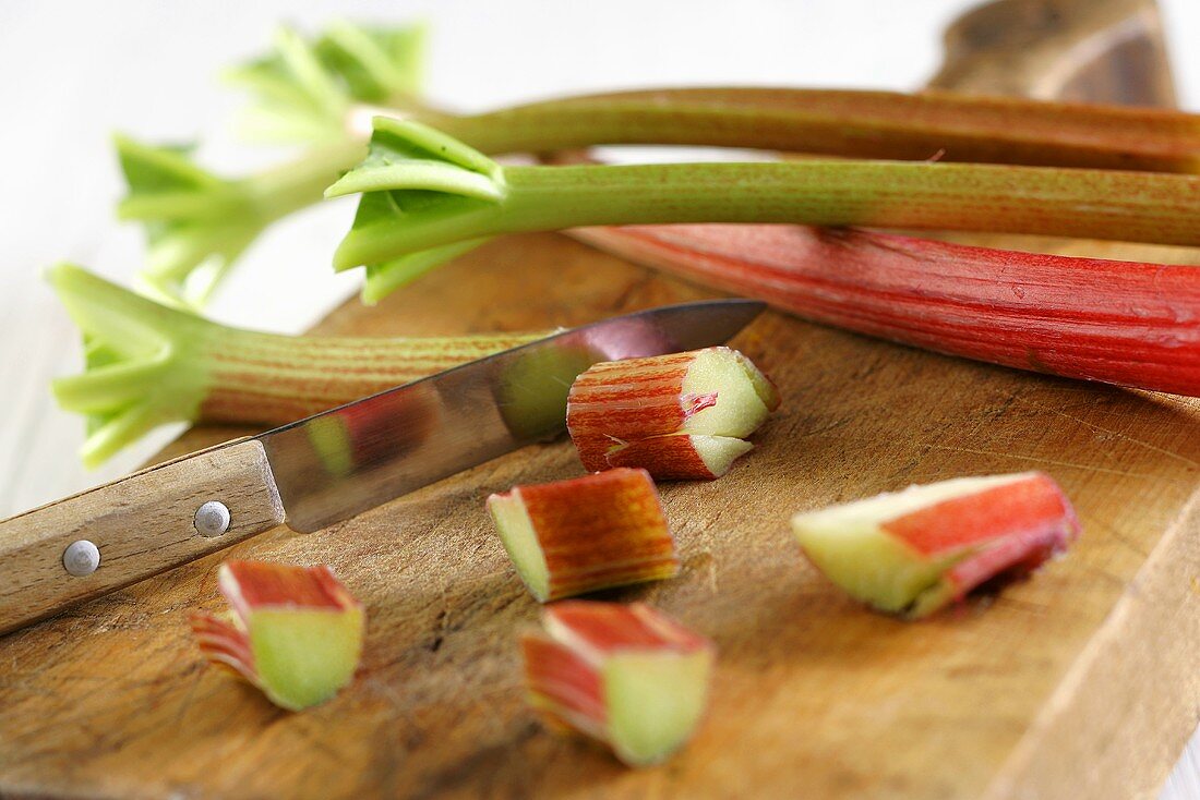 Rhubarb, partly sliced, on chopping board