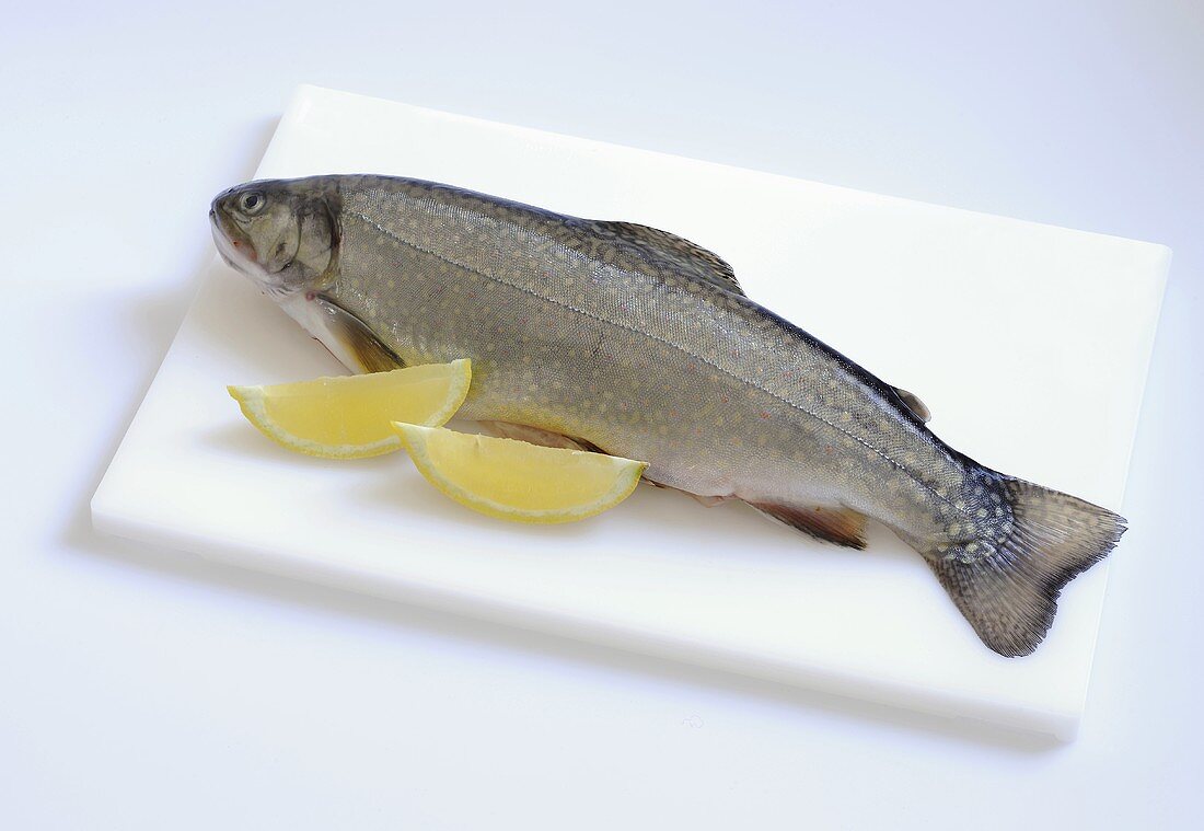A brown charr with lemon wedges on chopping board