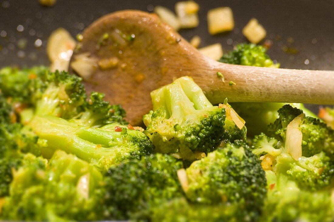 Brokkoligemüse in einer Pfanne mit Kochlöffel umrühren