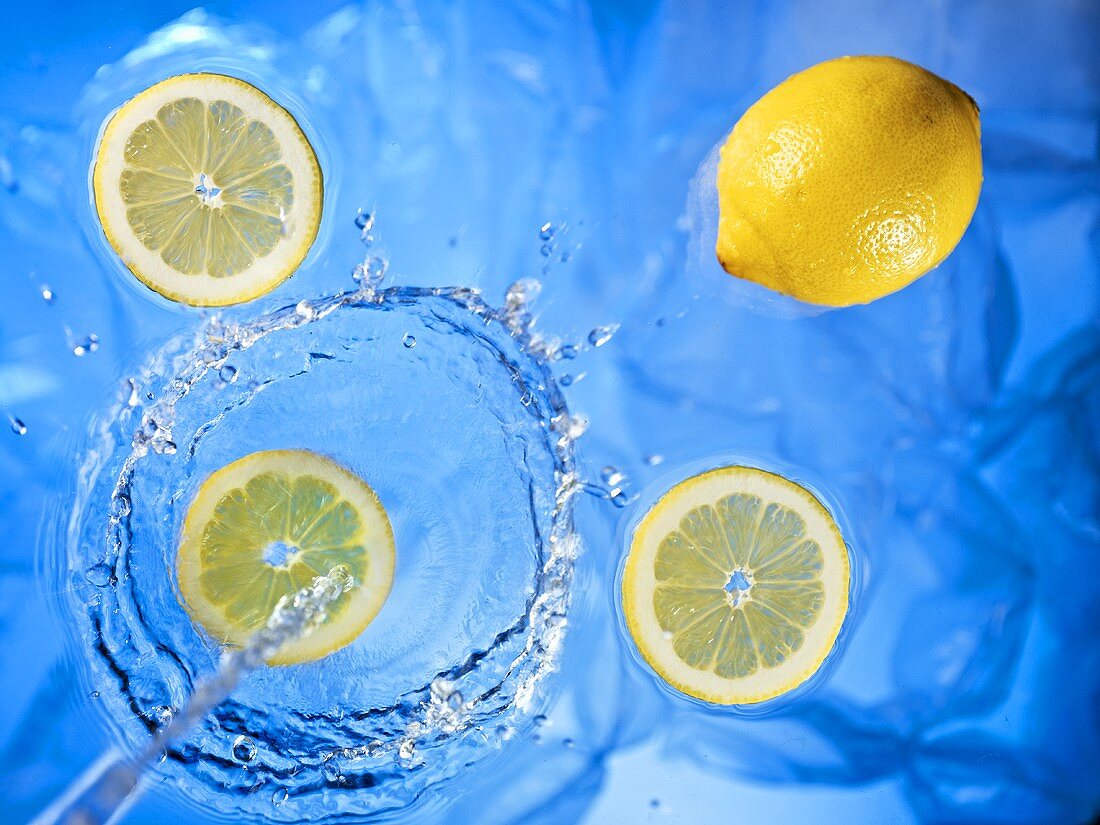 Stream of water running onto lemons and lemon slices