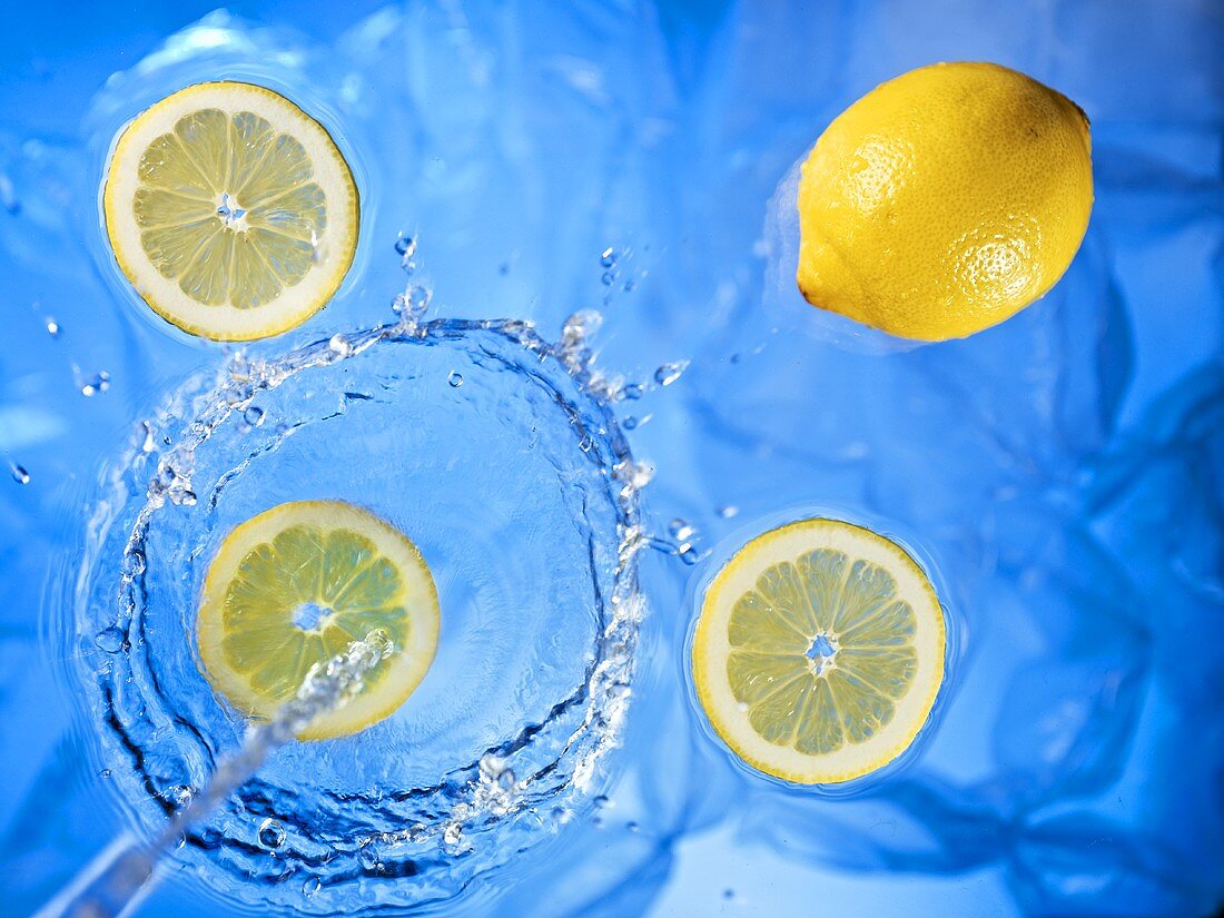 Wasserstrahl fließt auf Zitronen und Zitronenscheiben