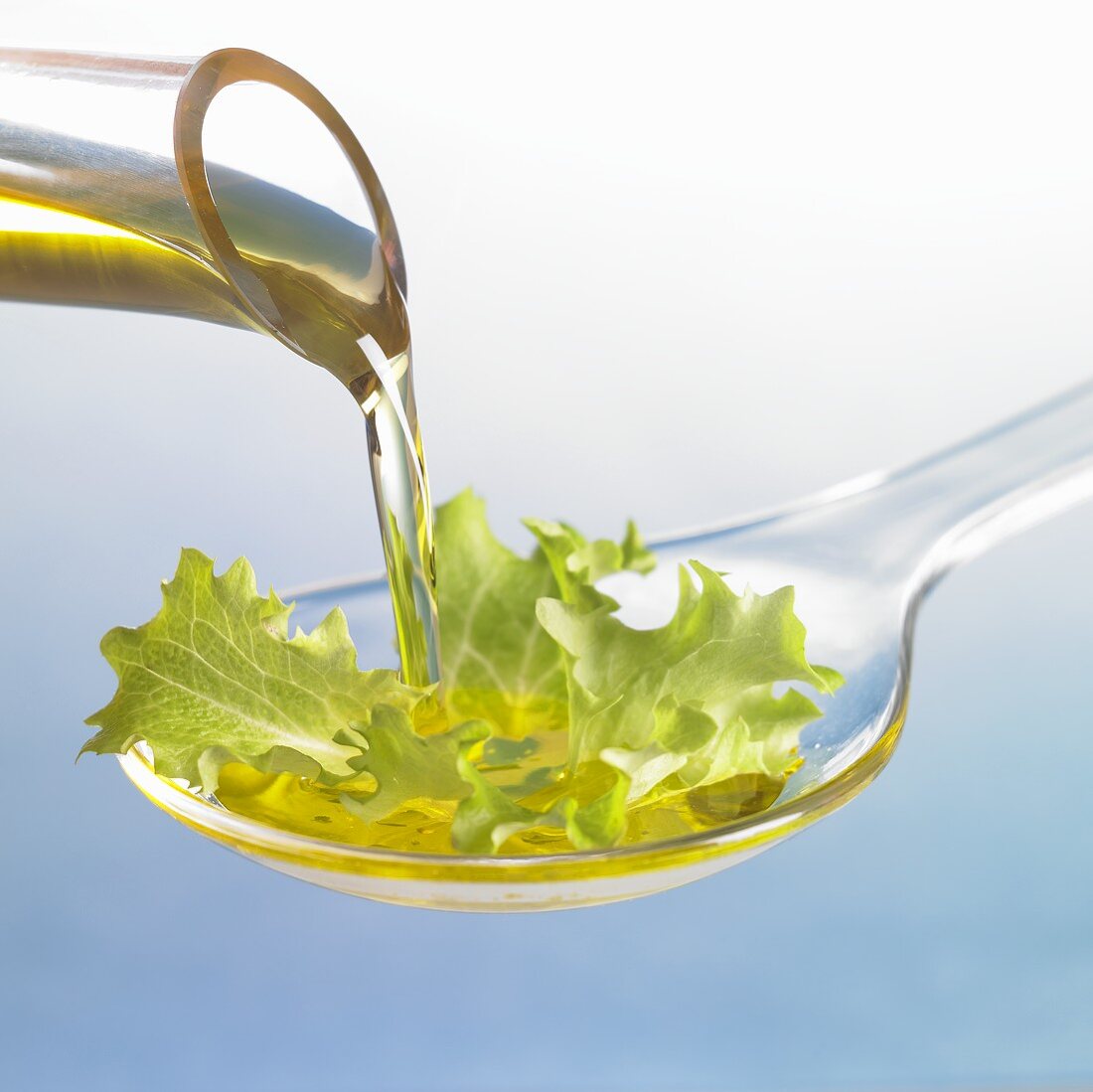 Öl fliesst auf Löffel mit Salatblatt