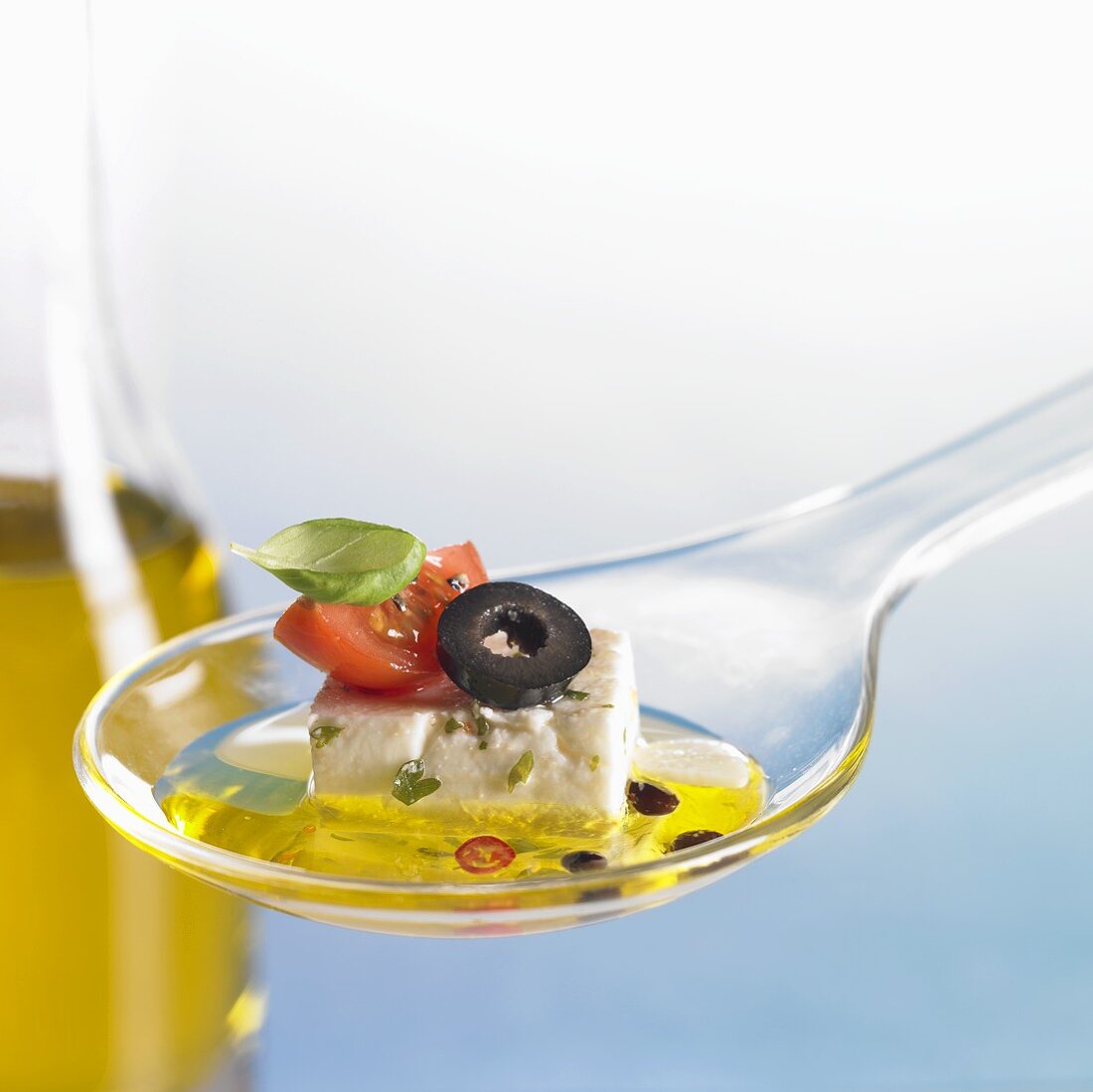Feta cheese with tomato, olive and oil on spoon