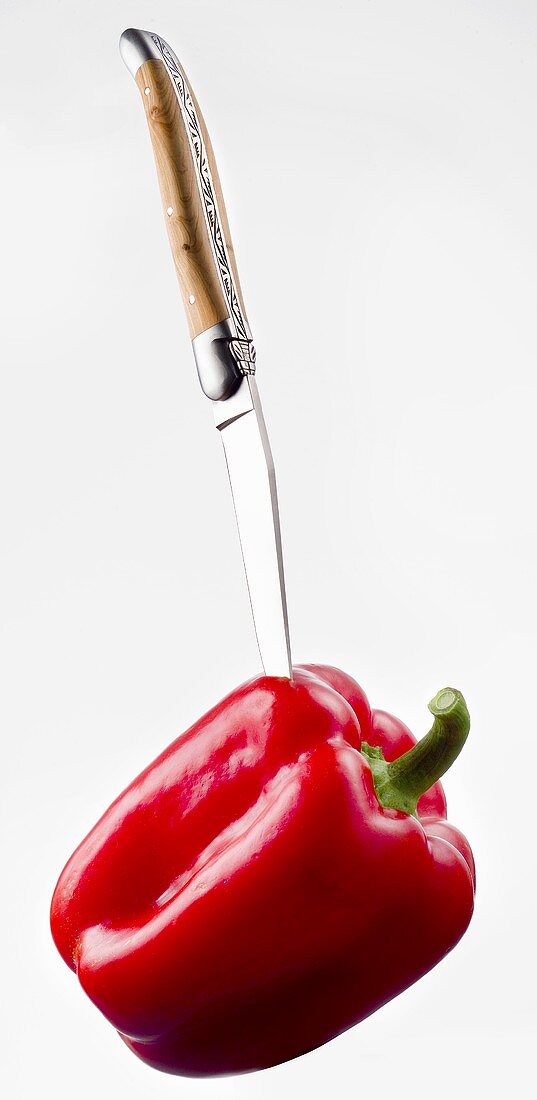 Knife sticking into a red pepper