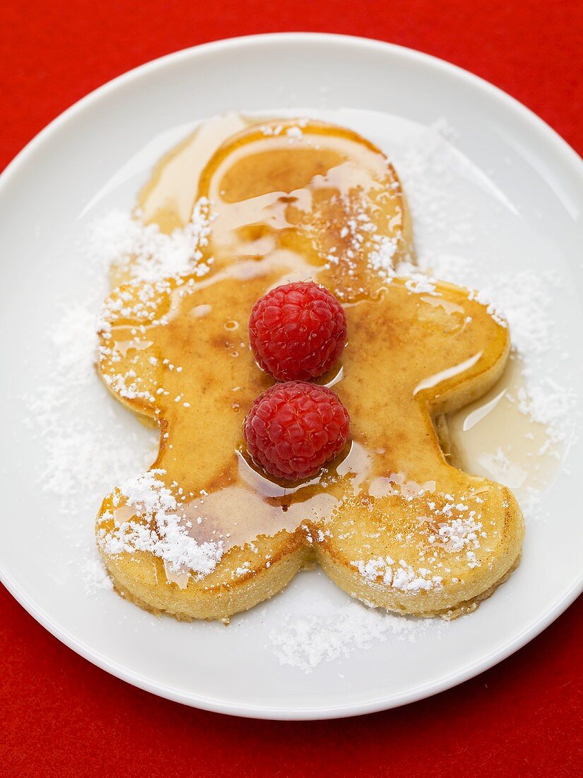 Pancake man with raspberries, icing sugar and maple syrup