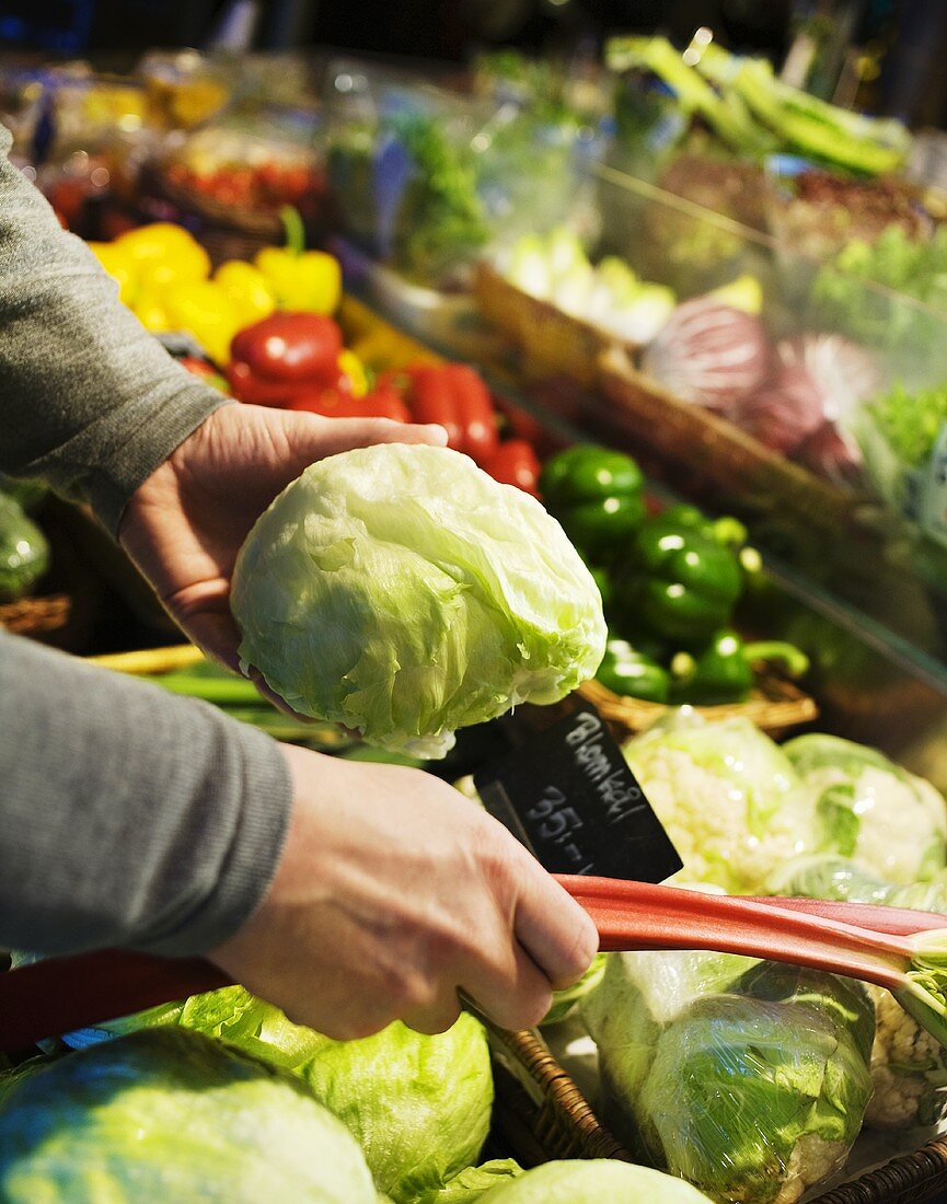 Person wählt Gemüse am Marktstand aus