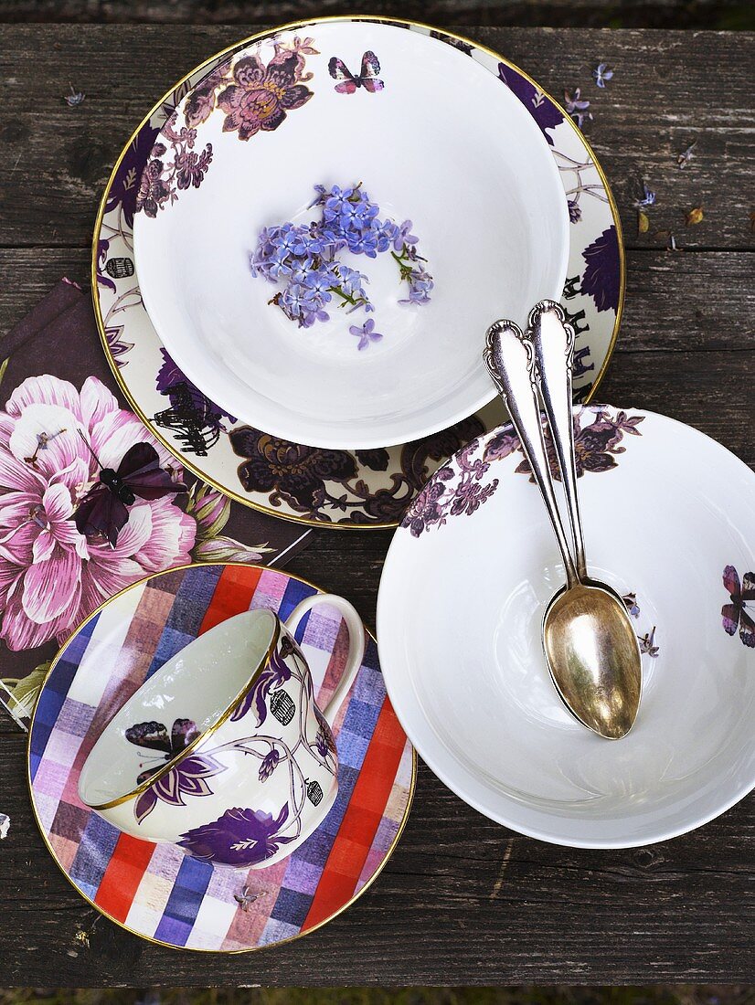 Plates, spoons and cups with saucers on a wood background