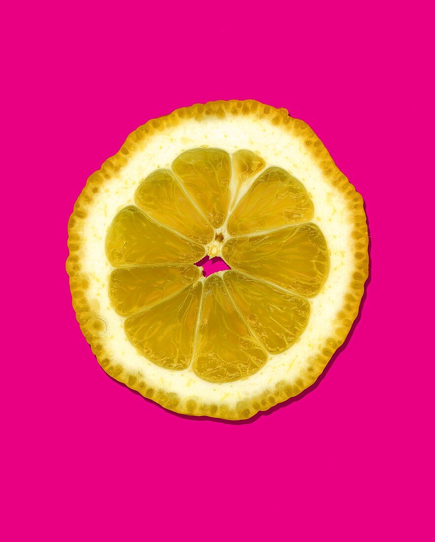 A slice of lemon against a pink background