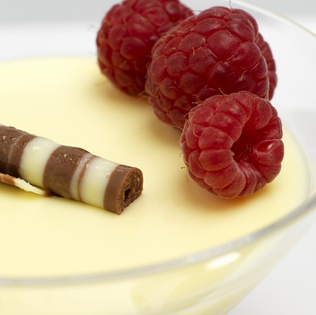 Zitronenpudding mit Schokoröllchen und frischen Himbeeren