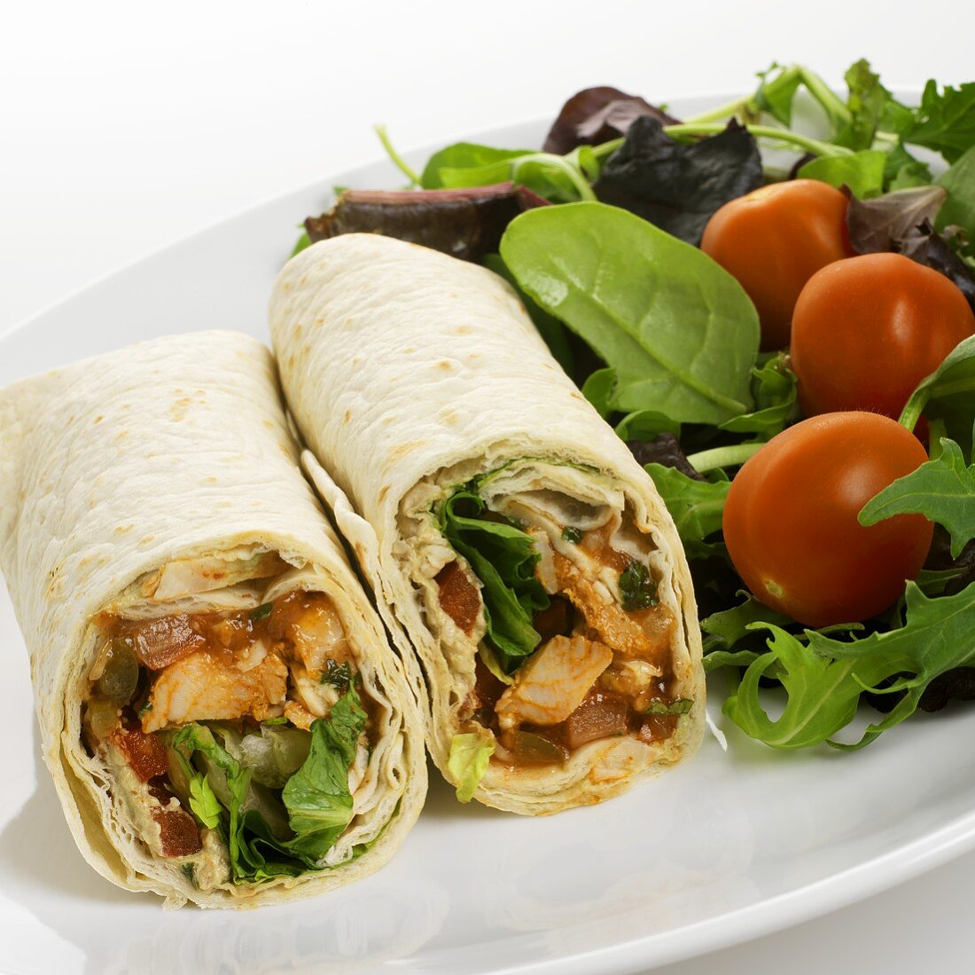 Hähnchen-Tomaten-Wrap mit Salatbeilage auf einem Teller