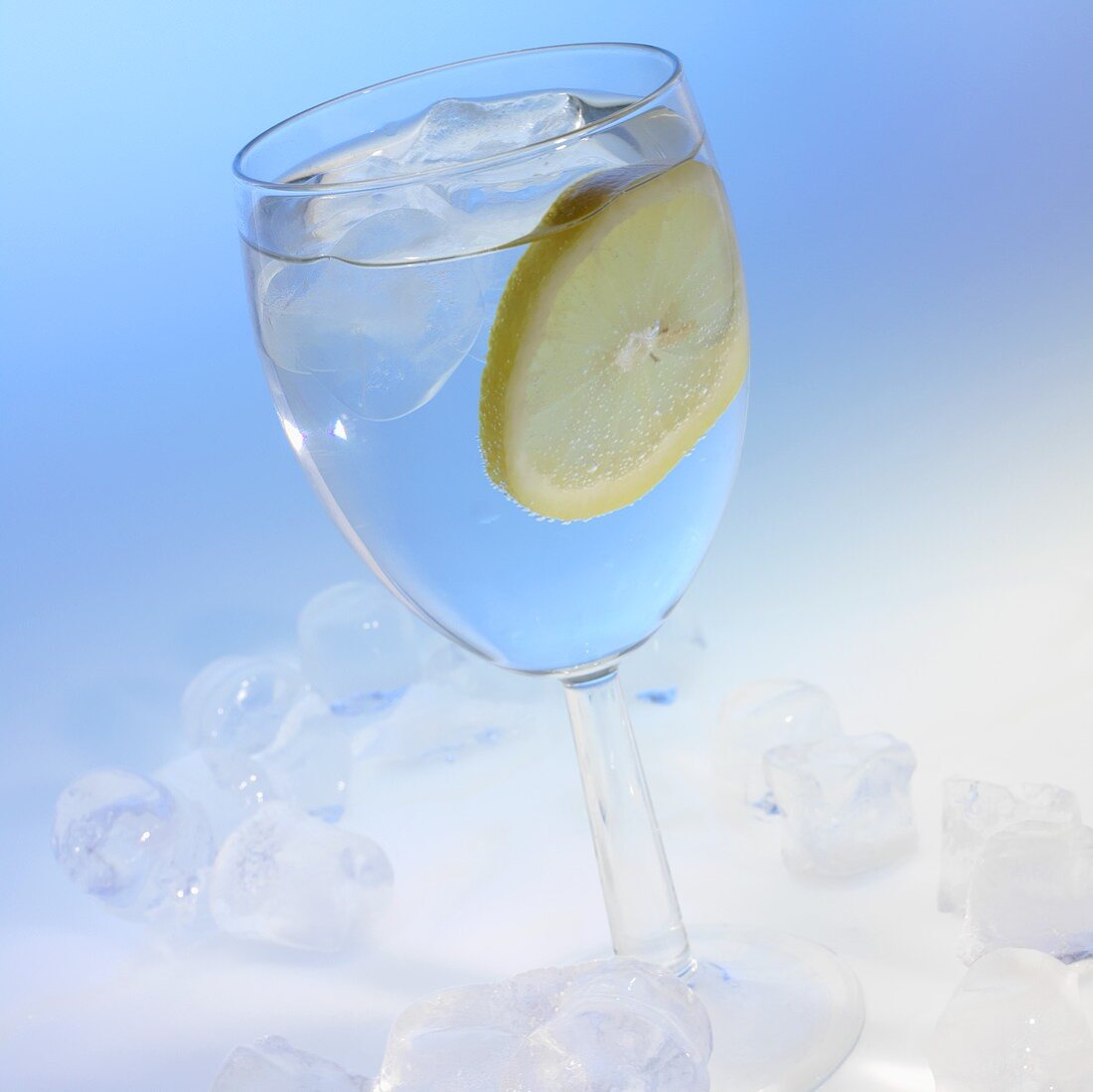 A glass of water with a slice of lemon and ice cubes