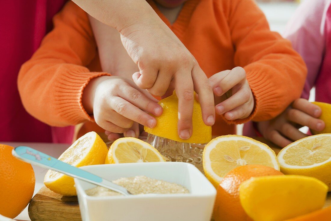 Children squeezing citrus fruit (for juice)
