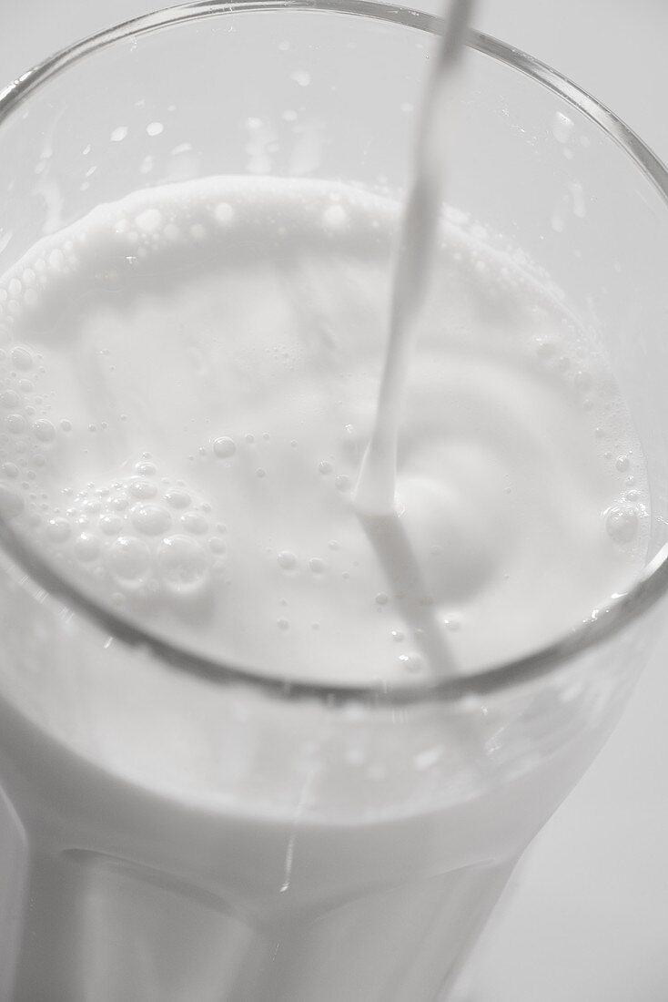 Milch wird in ein Glas gegossen