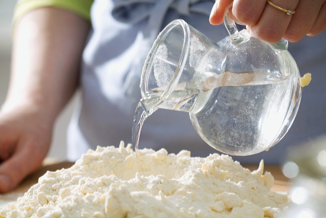 Kuchen backen: Wasser zu den Teigzutaten gießen