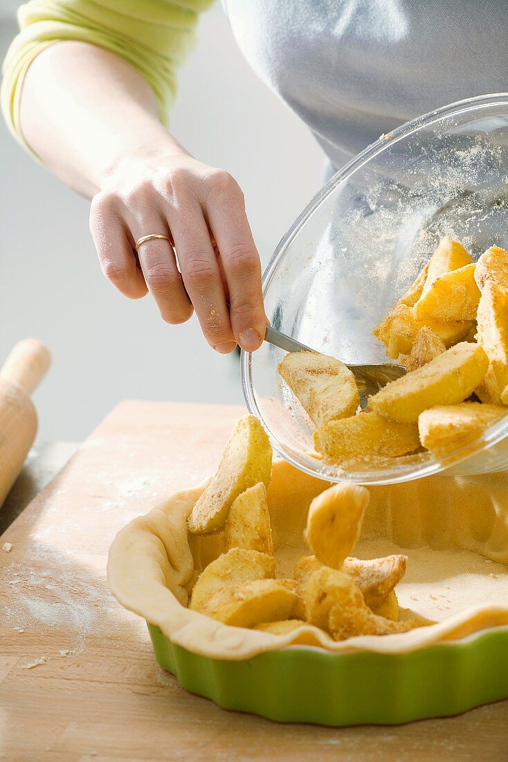 Making apple pie: putting apples into lined pie dish