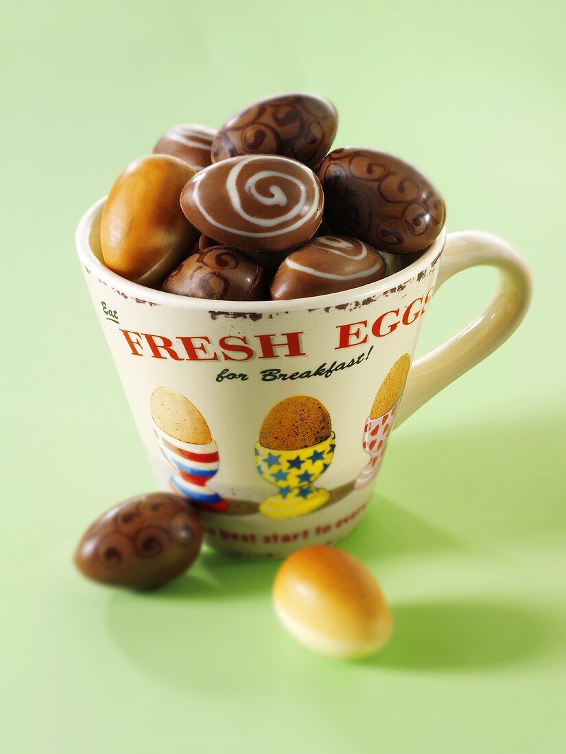 Chocolate eggs in and beside a cup