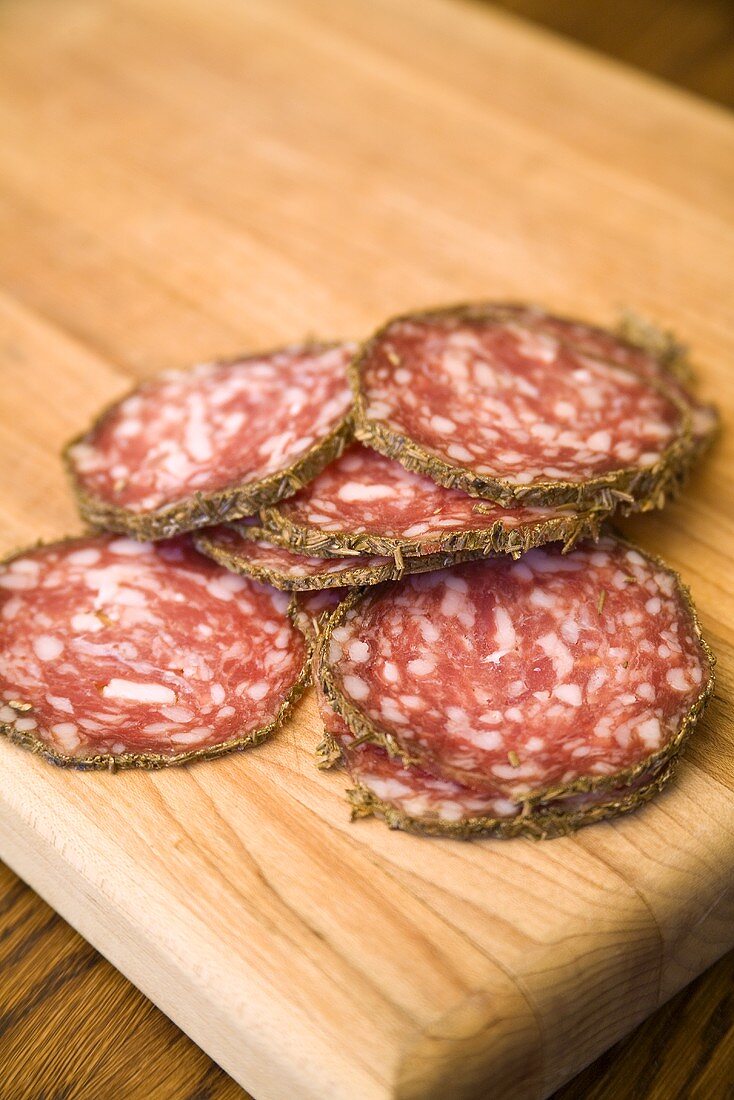 Several slices of salami on a wooden board